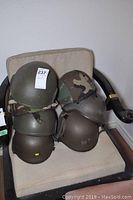 Front view of stacked helmets showing four on left and two on right atop an upholstered chair