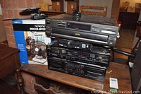 Photo showing all electronic items stacked on a table: Pioneer cassette player, JVC receiver, Diamond DVD CD player, Technics CD changer SL PD827, and boxed TV FM indoor antenna.