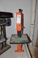 Front side view of the orange band saw on flat surface showing size, blade and working platform