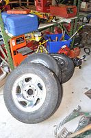 Three Michelin tires on steel rims arranged stacked, showing overall lot contents in garage environment.