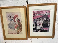 Two framed French art prints with solid wood frames hung on a white brick wall.