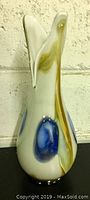 Front side view of handblown art glass vase showing white glass with blue and amber colored accents and split flared top rim