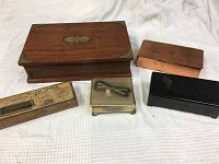 Five vintage storage boxes arranged on white cloth, showing variety in materials: wood, metal, copper, black lacquered.