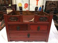 Front view of the wooden desk tray showing three drawers and carved decorative panels with animal motifs and carved posts at corners.