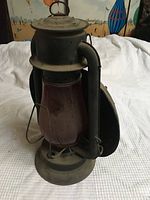 Front view of the vintage lantern showing metal construction and red glass globe.