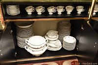 Full view of cabinet shelf with stacks of plates, bowls, cups, tureen, and serving pieces showing the floral patterned Werdel dinnerware set.