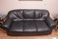 Front view of black leather sofa showing seat and back cushions, armrests.