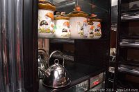 Shelf with five matching vintage ceramic canisters and a stainless steel kettle