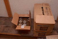 Three cardboard boxes containing clear glass canning jars, some with lids