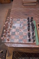 Full view of chessboard laid flat with all white and black marble chess pieces set in starting positions.