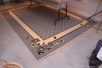 Full view of the rectangular rug laid on tile floor showing floral corner designs and lattice pattern in the center.
