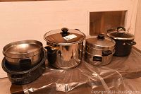 Full set of roaster and pots with lids arranged in a row on a table