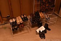 Five white metal shoe racks with multiple pairs of shoes arranged on and in front of them, showcasing the range and condition of footwear.