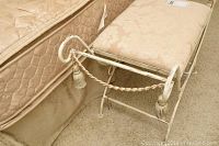 Close-up angled photo of the small bedroom bench showing wrought metal frame and upholstered seat.