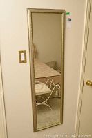Front view of full-length mirror showing reflective surface and decorative gold-tone frame.