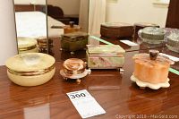 Four decorative boxes displayed on wooden dresser with mirror in background.