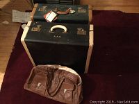 Photo shows two vintage Lincoln Zephyrweight suitcases stacked with brown leather bag in front on floor.