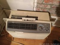 Full view of beige Siesta by Carrier window air conditioner showing air vents and front grille