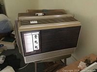 Vintage General Electric Fashionette window air conditioner unit whole view in room with some background clutter.