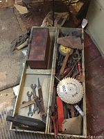 Overview of open wooden toolbox with various vintage tools inside, showing the full contents and condition.