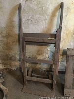 Full view of vintage iron hand truck standing upright showing metal frame, wheels, and curved handles
