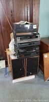 Photo of stacked stereo components on top of wooden frame speakers, showing size, style, and condition of equipment.