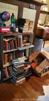 Bookshelves filled with stacked and organized books in various conditions, with some boxes of books on the floor nearby.