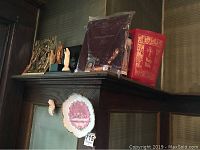 Religious artifacts displayed on shelf including Holy Bible, wall plaques, and figurine statues