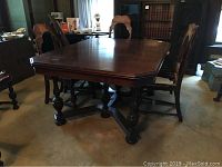 Full view of rectangular Jacobean style dining table with four ornate bun feet and turned stretcher supports. Table top has dark finish with slight surface wear. Four Jacobean style chairs partially visible around table.