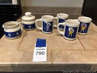 Full view of the 7-piece Morton Salt coffee set including 4 mugs, creamer, sugar bowl with lid on kitchen counter.