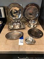 Full view of all nine silverplate pieces including trays, gravy boat, plates, lidded server, and small bowls.