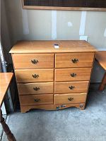 Front view of the 8 drawer dresser showing wood grain, metal handles, and some wear.