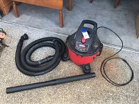 Craftsman shop vacuum with hose and wand shown on ground near wood furniture.