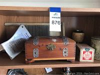 Photo showing small wooden chest with metal detailing, small metal washboard behind it, and two tea tins next to it.