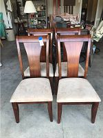 Front view of the four dark wood dining chairs with cream microfiber upholstered seats, showing general condition and design.
