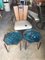 Photo showing vintage chair with wooden backrest and vinyl seat cushion alongside two octagonal blue resin top accent tables with wooden legs, all placed in a garage environment.