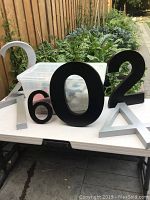 Cast aluminum numbers '6', '0', '2' in black finish with a large silver number '4' and additional numbers in background, showing size and font variety