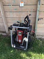 Pressure washer unit with frame collapsed; hoses, spray gun and lance attached