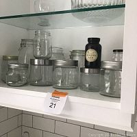 13 assorted glass jars in various sizes and lid styles arranged on a shelf