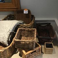 Photo showing several baskets, including large round basket with cloth liner, rectangular and square baskets in natural and dark wicker