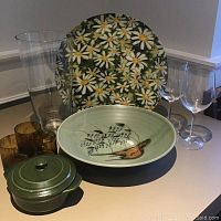 Photo showing all the items together: vintage plastic daisy pattern tray, tall clear glass vase, ceramic serving dish with bird design, two tortoise shell tea light holders, two wine glasses, and small green ceramic lidded dish.