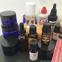 Close-up of essential oils and jars including Trader Joe's Lemon Essential Oil, amber dropper bottles, and blue glass jars