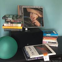 Stack of books and vintage LP records with teal glass globe light on table