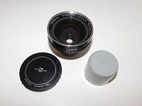 Photo showing lens next to rear white lens cap, demonstrating included accessories.