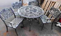 Wide view of round metal patio table and four chairs showing structure and paint wear