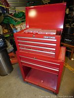 Front angle view showing top chest open with organizer boxes visible, multiple drawers below, and lower base cabinet open shelving with wheels.