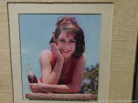 Front view of the vintage Pepsi advertising art showing woman in red top holding glass Pepsi bottle, matted and framed under glass.