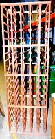 Full view of tall wooden wine rack showing multiple horizontal bottle slots and vertical sections.