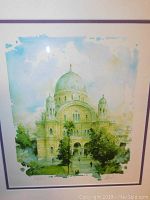 Close-up of signed and numbered watercolor style print featuring a beige building with domes and greenery.