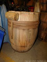 Full view of the wooden wine barrel with metal strapping, showing no lid and signs of wear.